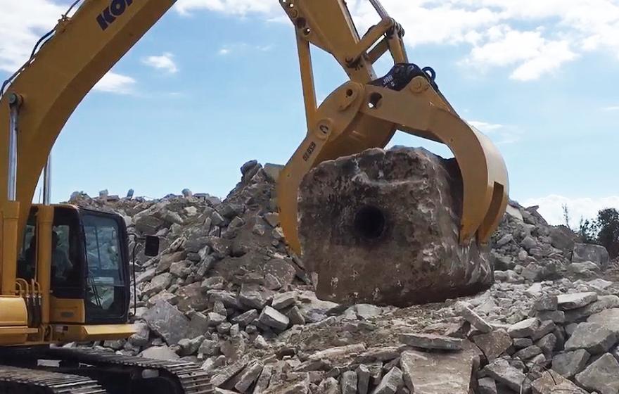 Yellow GSD C grapple lifting cement block